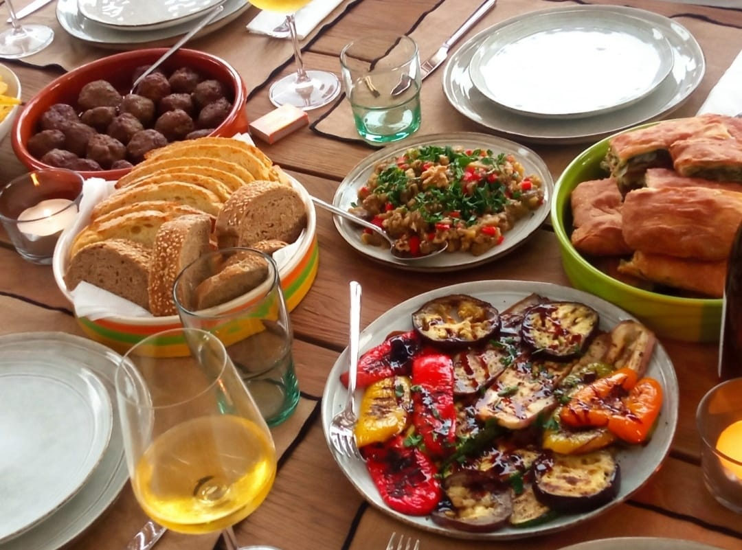 Grilled vegetables, bread and wine on a terrace table